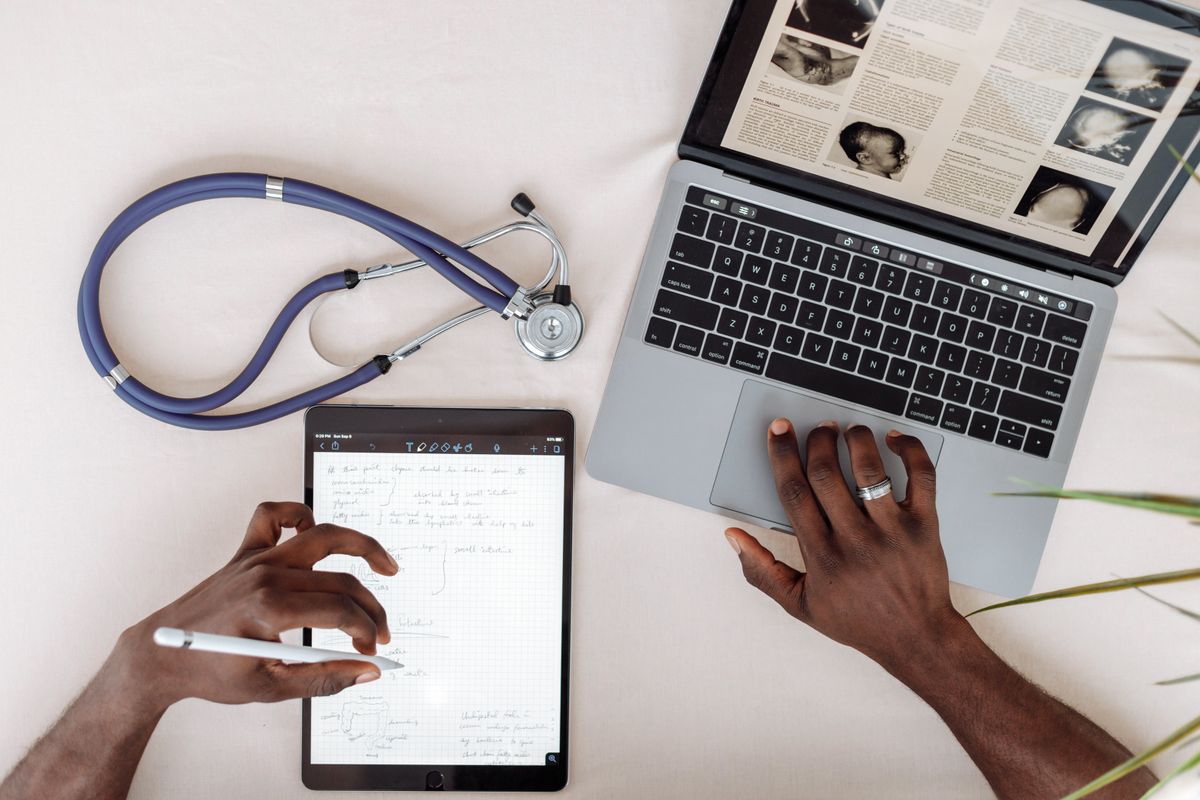 A healthcare professional reviewing a verified provider record on a laptop and tablet, instead of paper forms